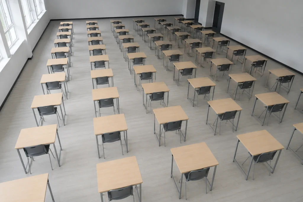 Sala de prova vista de cima com carteiras individuais alinhadas em grade e todas vazias