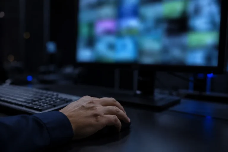 Console de monitoramento logístico com tela desfocada e mão sobre o mouse.