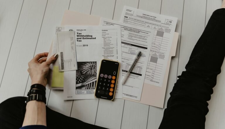 Mãos conferindo planilha ao lado de calculadora e caneta