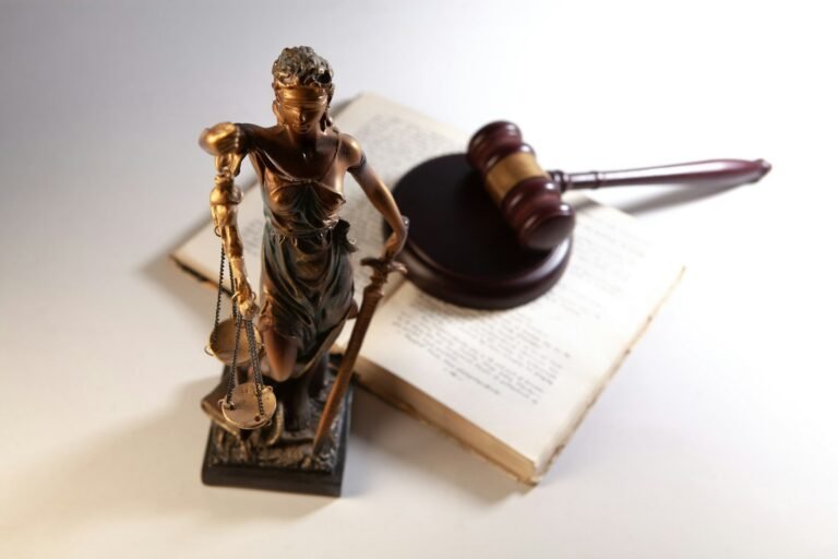 Estatua da justica ao lado de martelo e livros de direito
